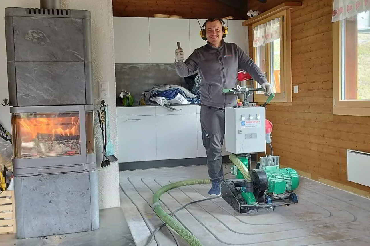 Ein Mann steht vor einem Holzofen, während er einen Fräsjet in der Hand hält.