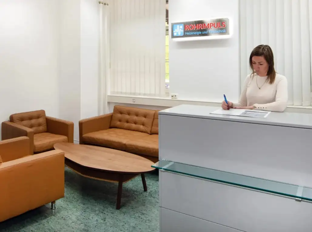 Eine Frau schreibt an einem Schreibtisch in einem Büro.