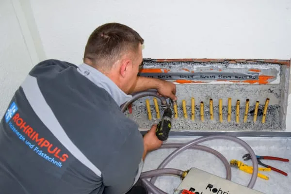 Ein Mann reinigt eine Heizung mit einem Reiniger.