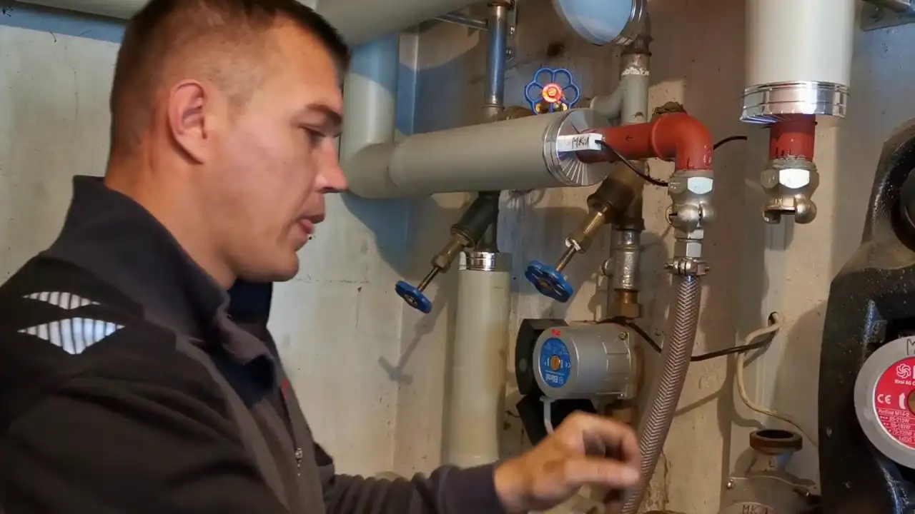 Ein Mann arbeitet an einer Heizung in einem Raum.